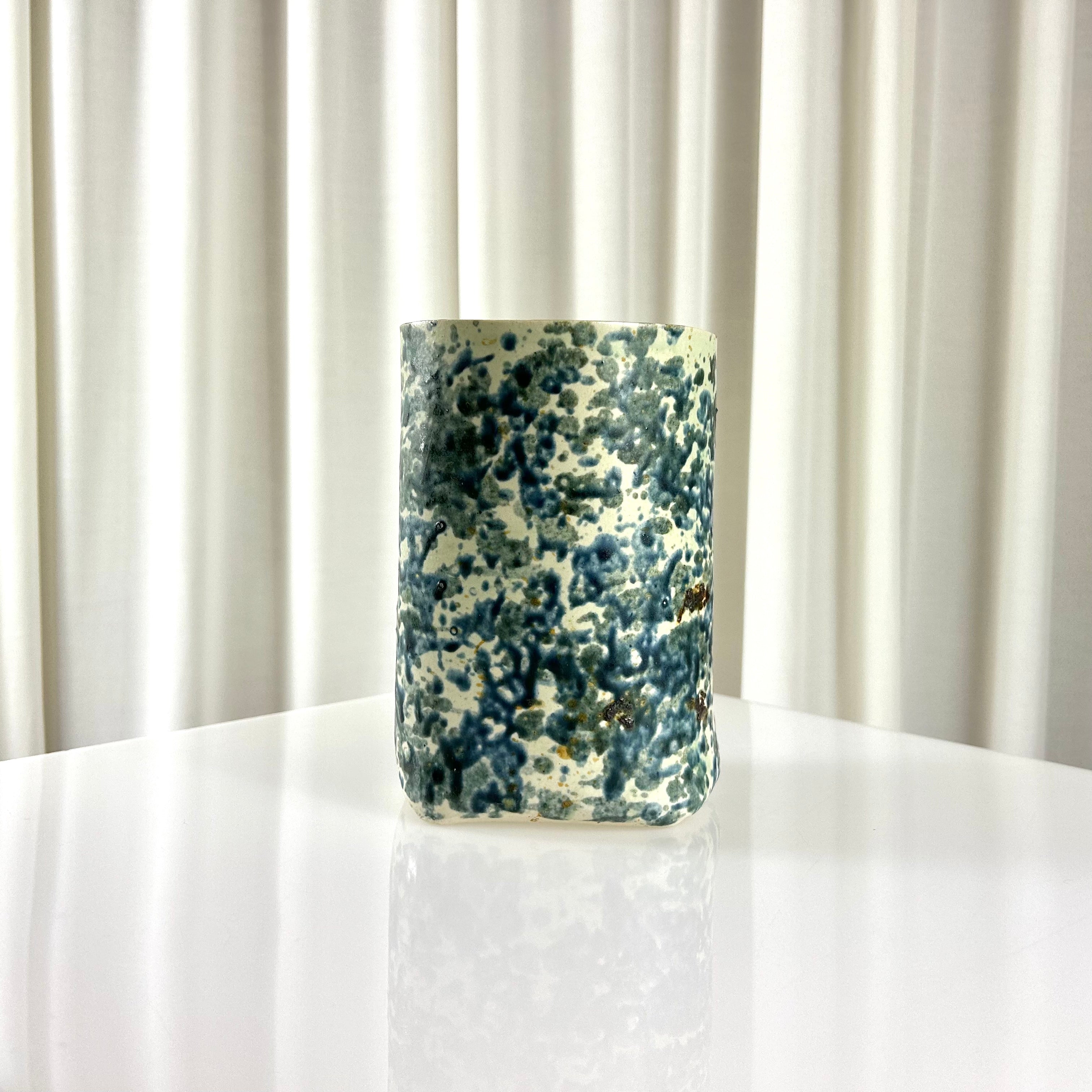 Backside of a vintage ceramic vase with blue speckles