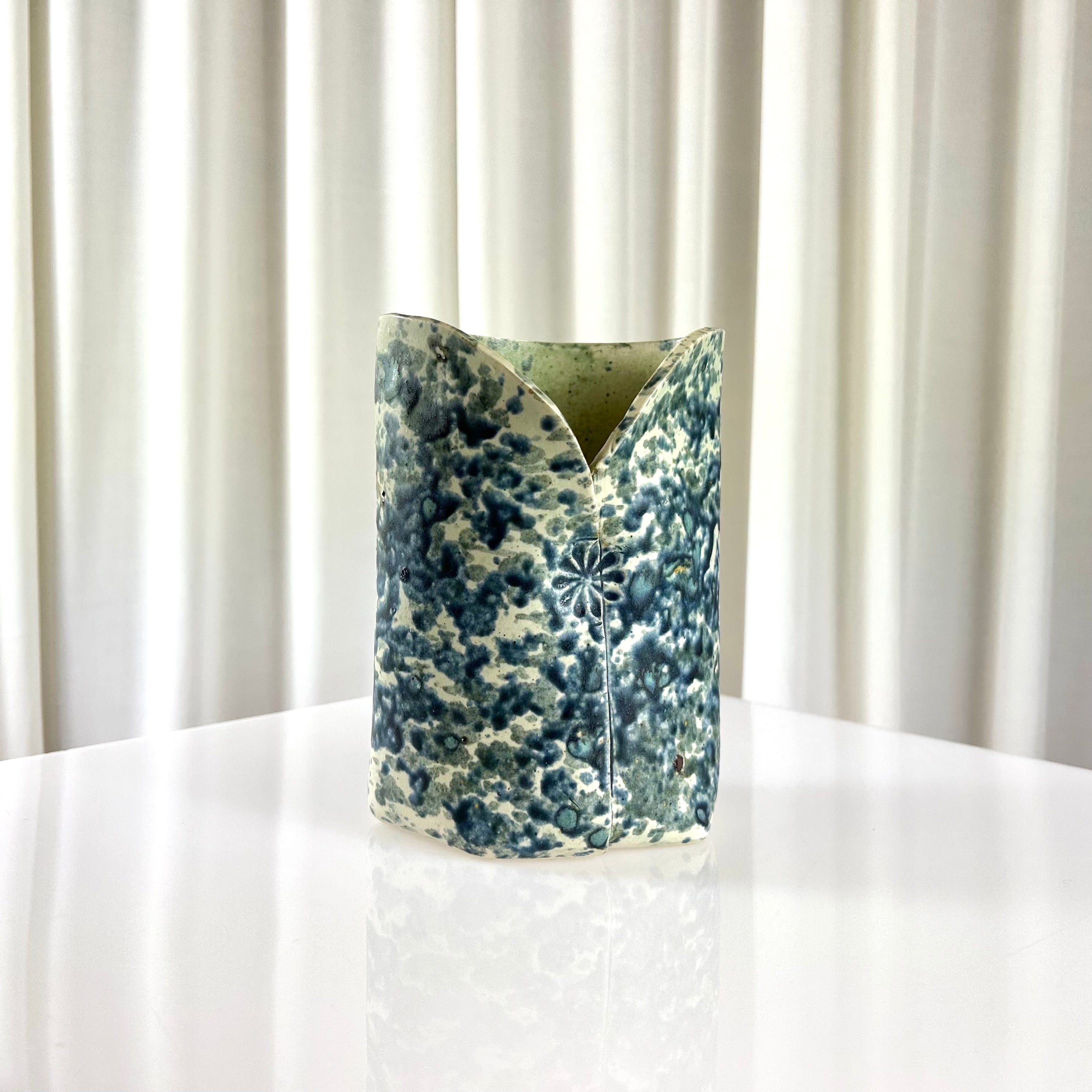 Front of a ceramic vintage vase with blue speckles