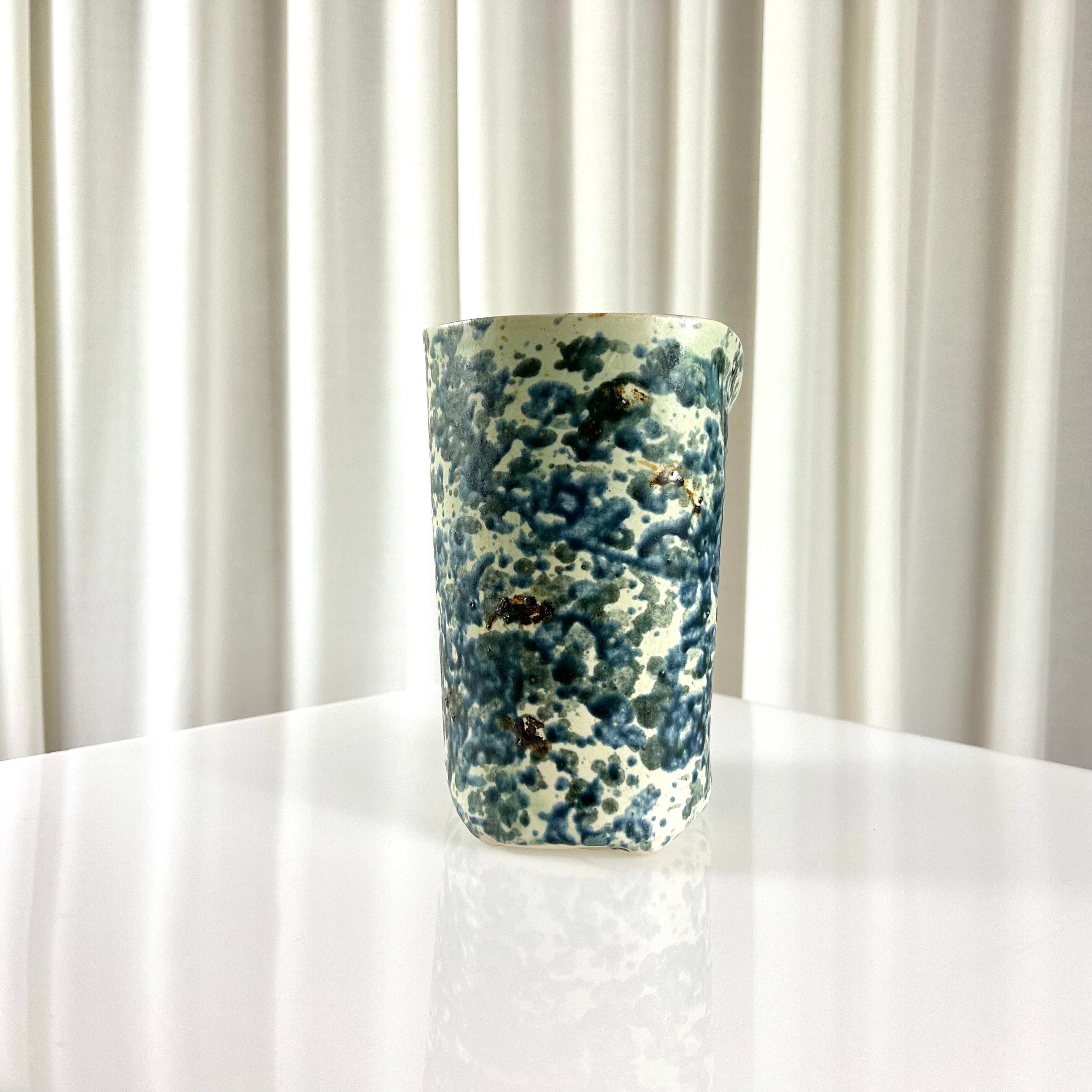 Side of a vintage ceramic vase with blue speckles