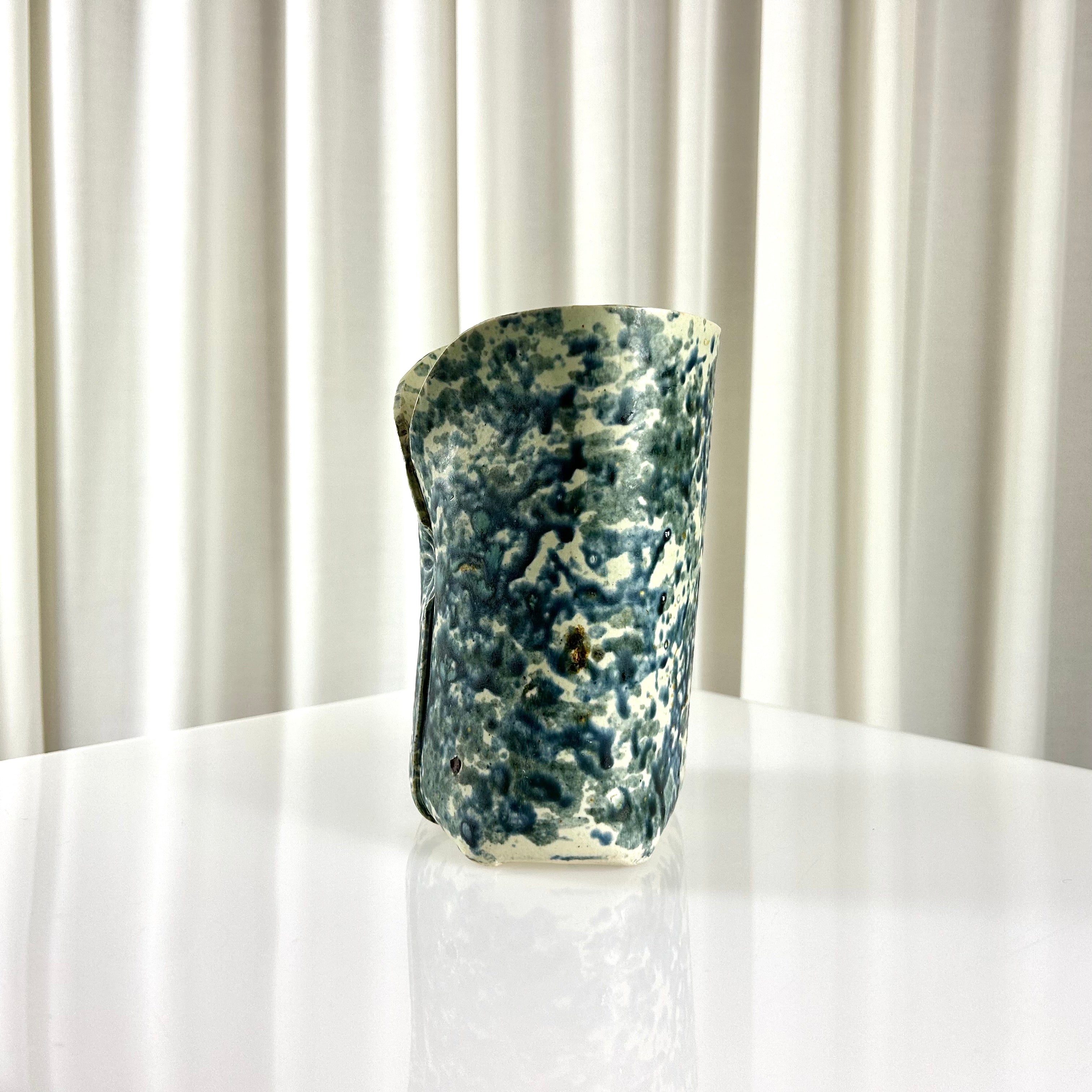 Side of a vintage ceramic vase with blue speckles