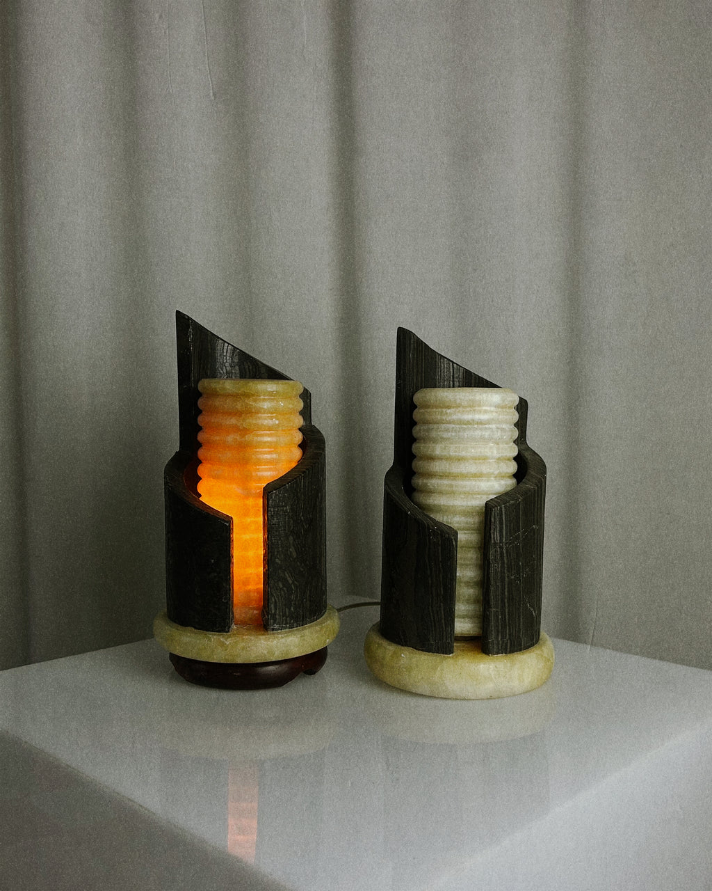 A pair of postmodern table lamps made of solid dark marble with fluted internal alabaster columns.