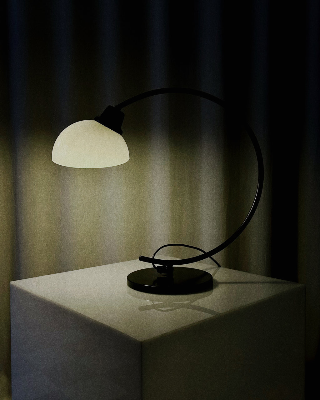 Vintage IKEA Harmoni table lamp featuring a black arched metal frame and a white glass shade, 1980s postmodern design.