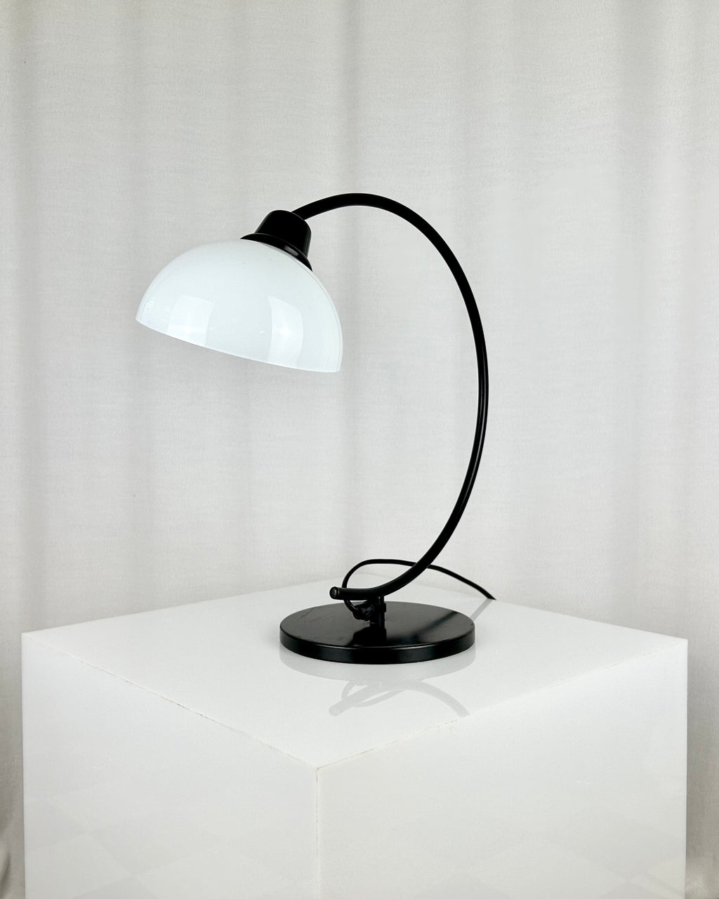 Vintage IKEA Harmoni table lamp featuring a black arched metal frame and a white glass shade, 1980s postmodern design.