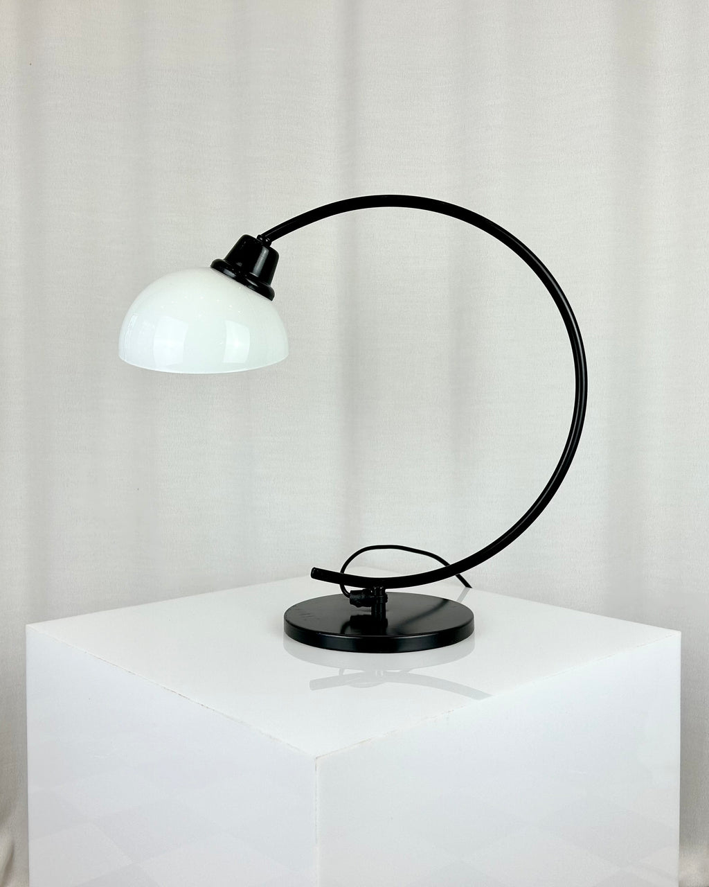 Vintage IKEA Harmoni table lamp featuring a black arched metal frame and a white glass shade, 1980s postmodern design.