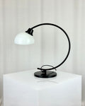 Vintage IKEA Harmoni table lamp featuring a black arched metal frame and a white glass shade, 1980s postmodern design.