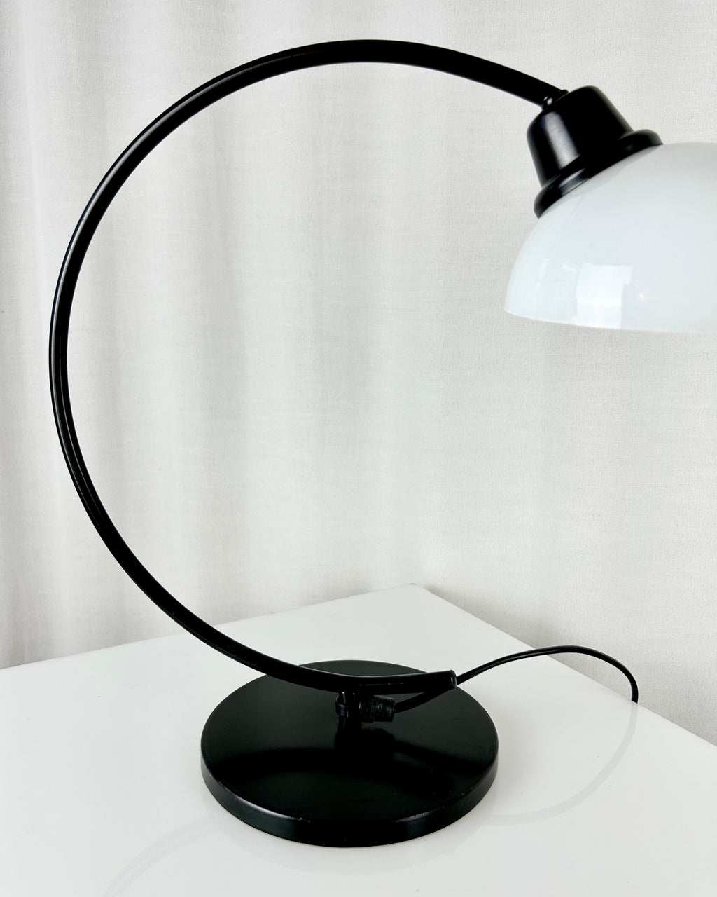 Vintage IKEA Harmoni table lamp featuring a black arched metal frame and a white glass shade, 1980s postmodern design.