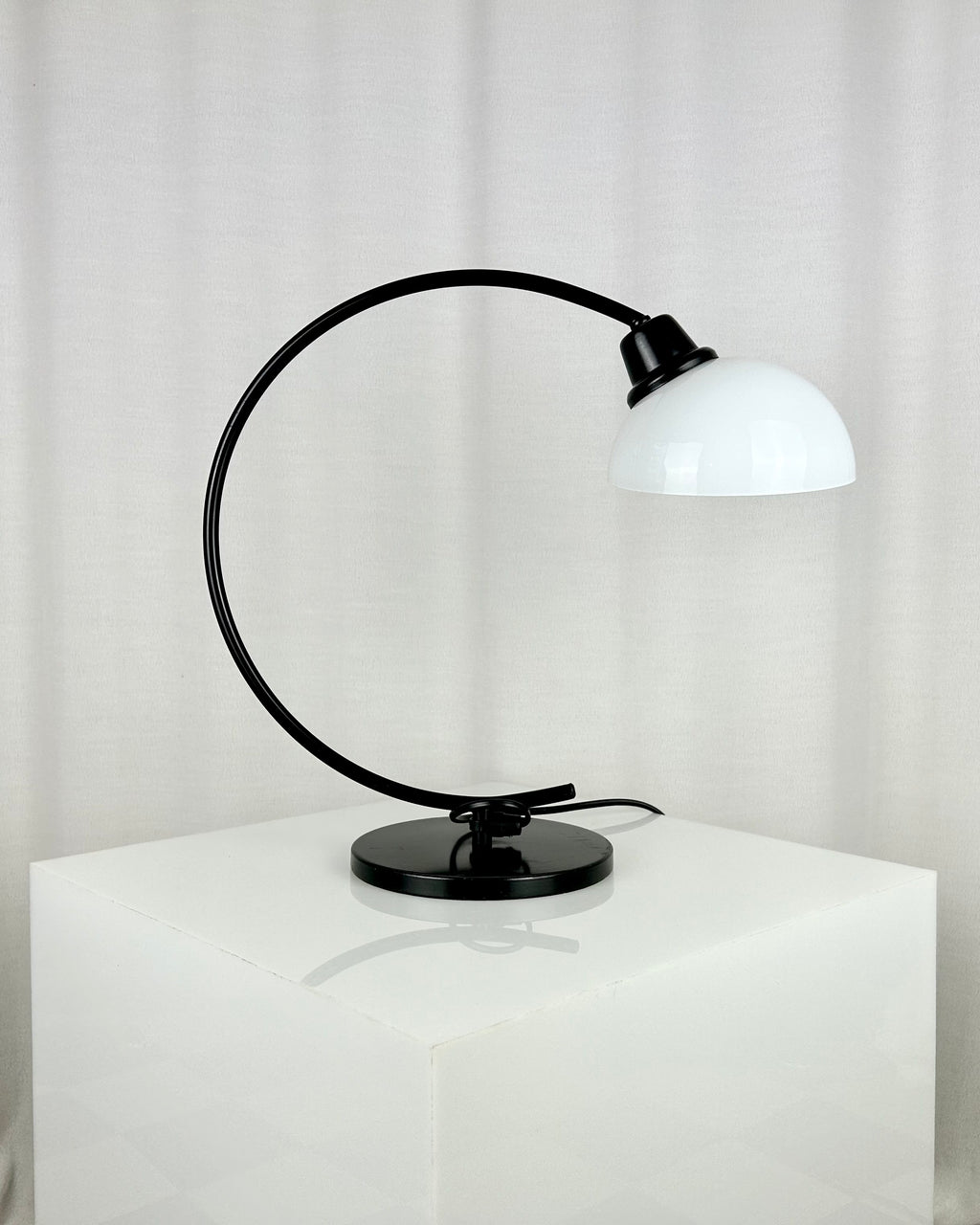 Vintage IKEA Harmoni table lamp featuring a black arched metal frame and a white glass shade, 1980s postmodern design.
