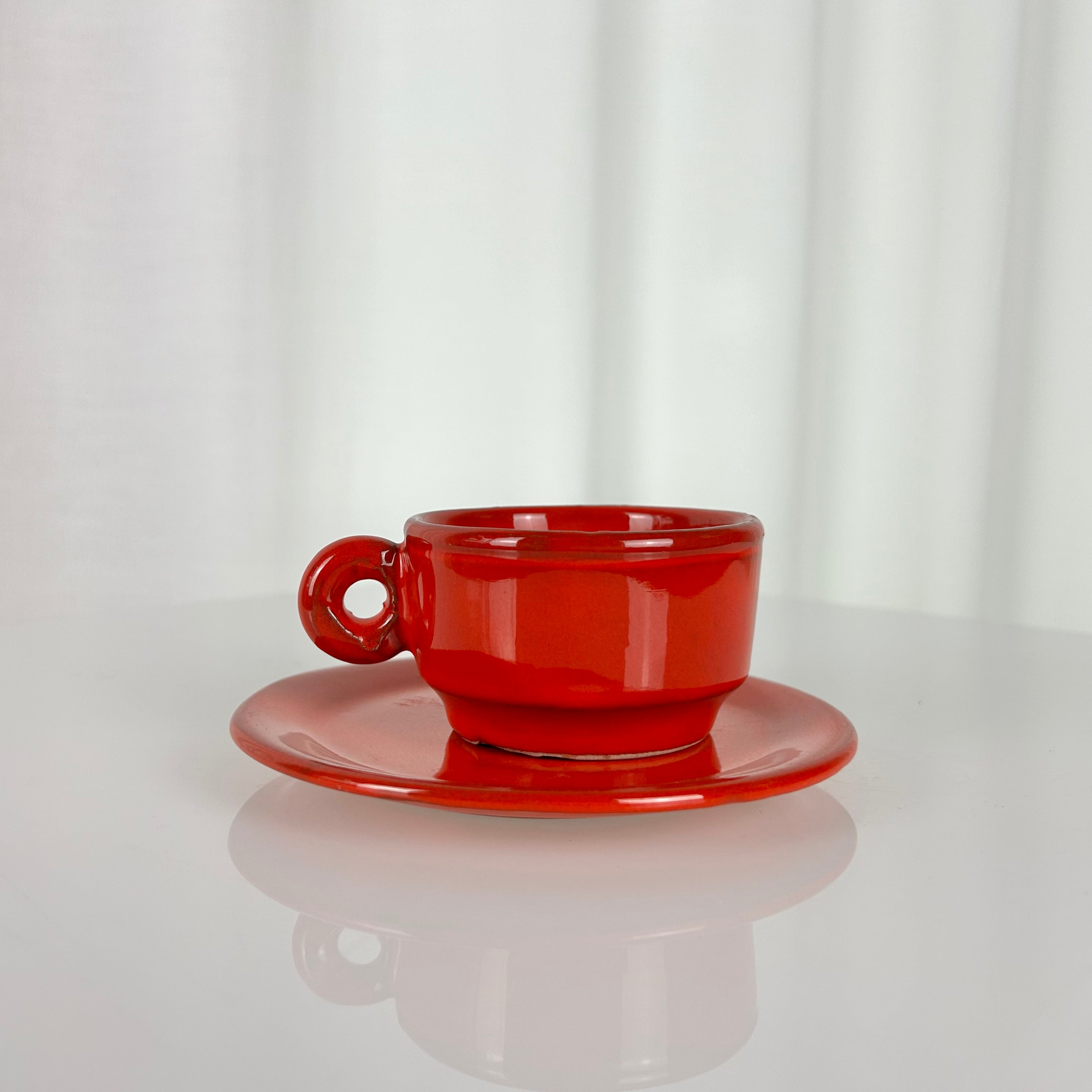 Closeup of a vintage red ceramic coffee cup and saucer set from the 1970s with pot, sugar bowl, cups and saucers
